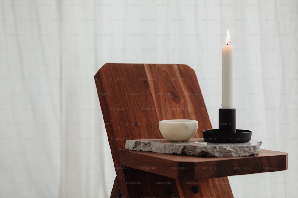 a white candle sitting on top of a wooden chair