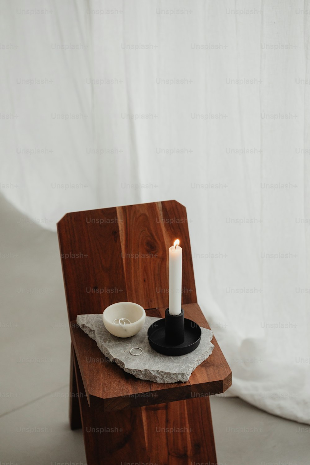 uma cadeira de madeira com uma vela em cima dela