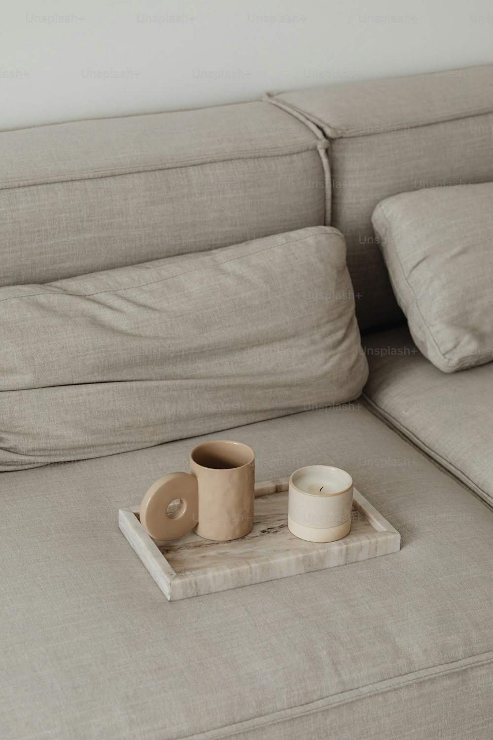a tray with a cup and a candle on a couch