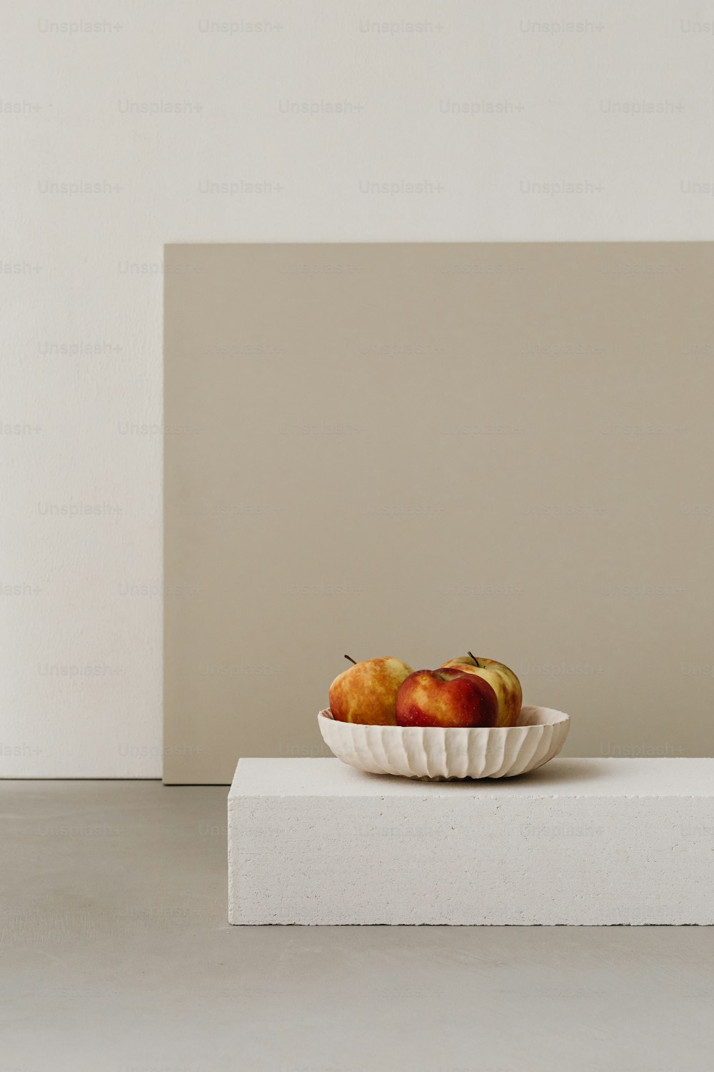 a bowl of fruit sitting on top of a white block