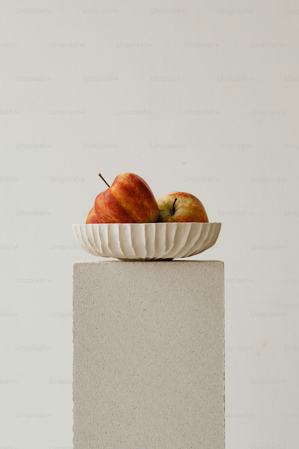 Zwei Äpfel in einer weißen Schale auf einem Sockel