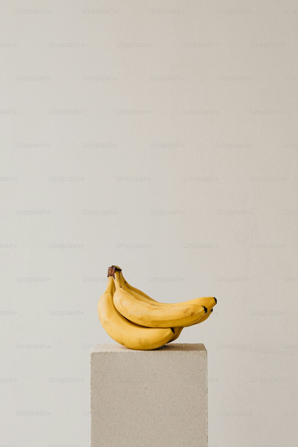 a bunch of bananas sitting on top of a white block