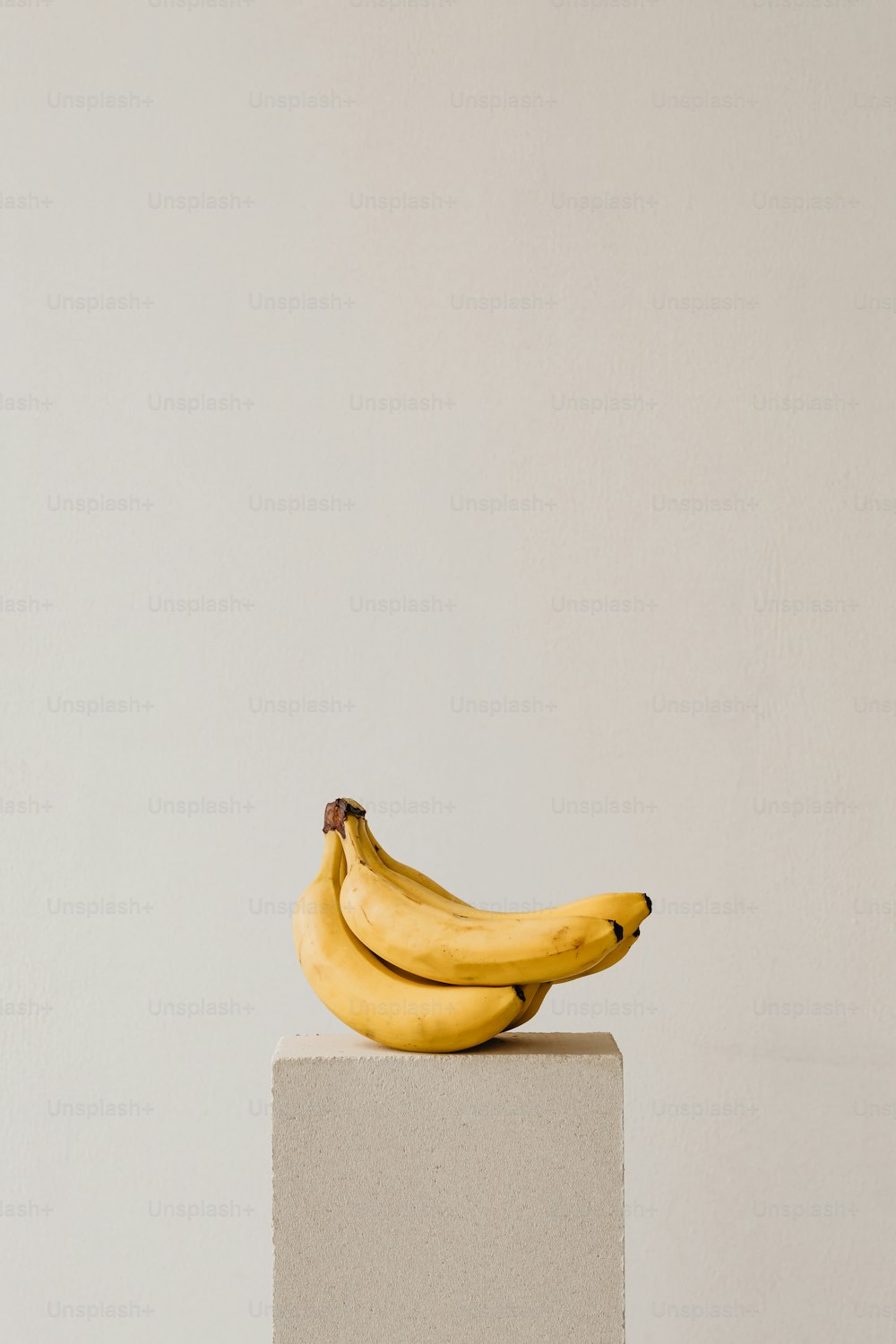 a bunch of bananas sitting on top of a white block