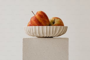 un bol blanc avec deux pommes dedans