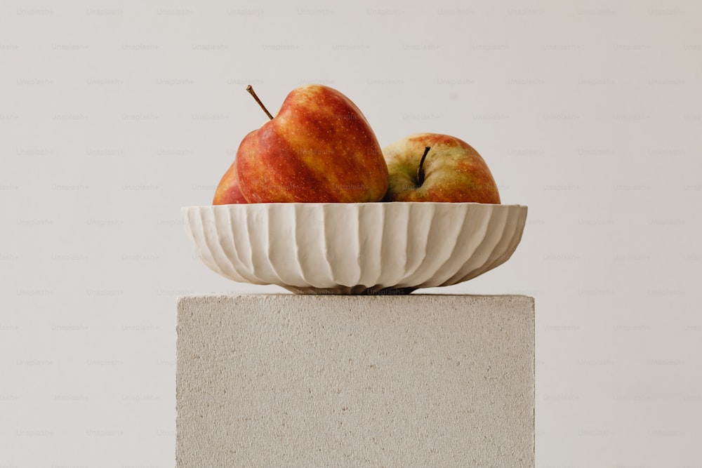 a white bowl with two apples in it