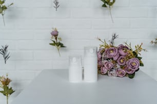 una mesa blanca cubierta con dos botellas de loción junto a un ramo de flores