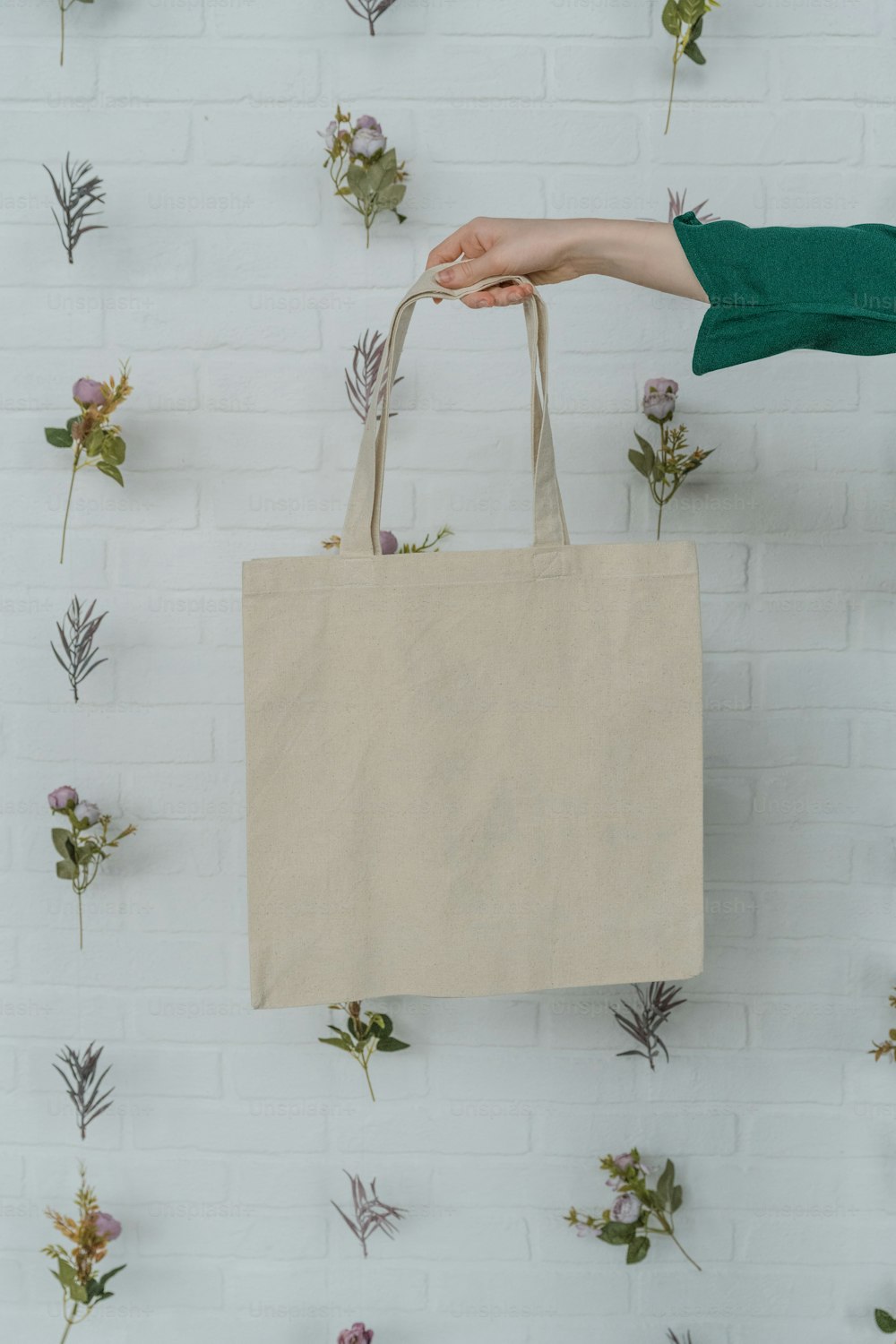 a person holding a shopping bag in front of a wall of flowers