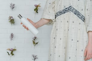 Eine Frau in einem weißen Kleid, die eine weiße Flasche hält