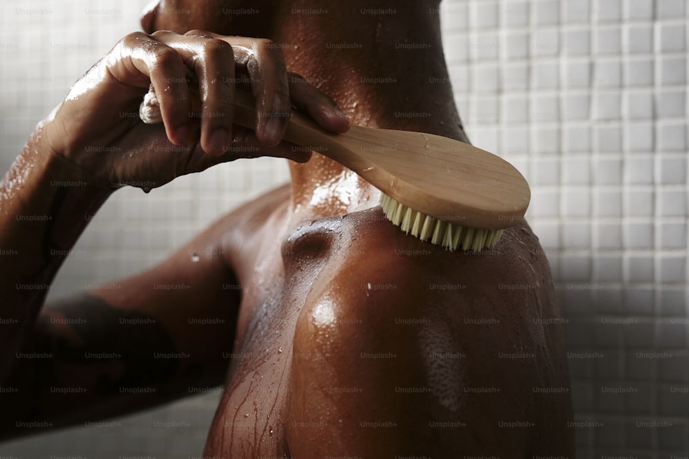 Ein Mann, der seinen Körper mit einer Holzbürste bürstet