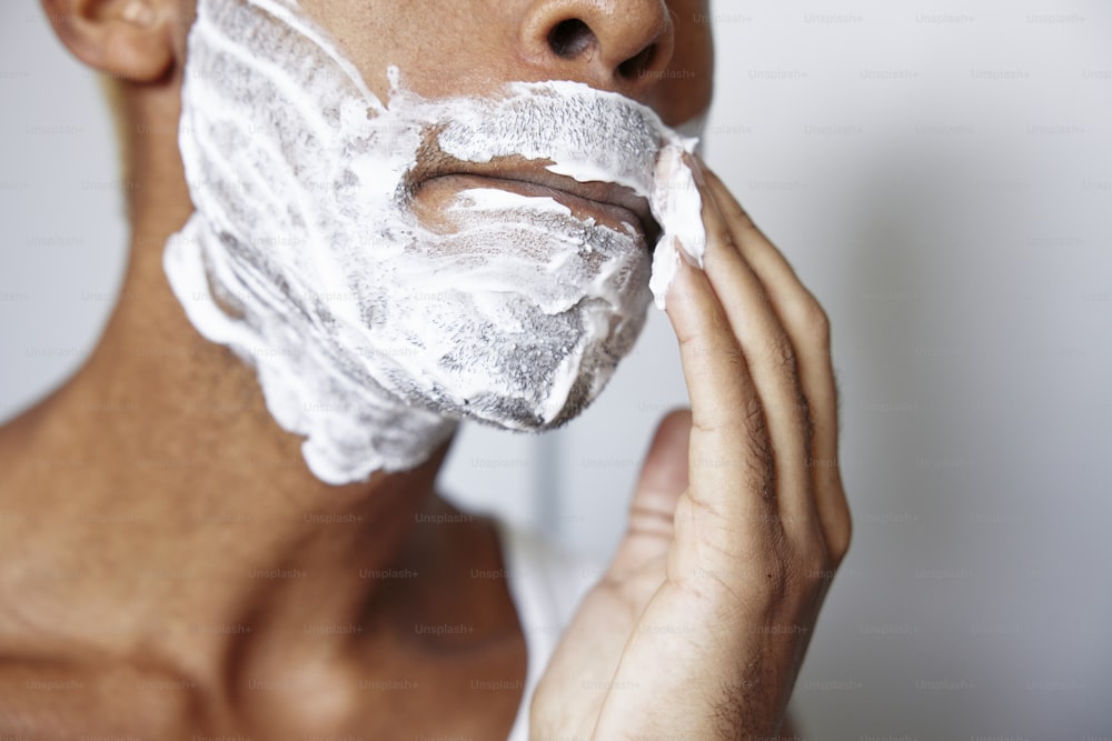 um homem raspando o rosto com uma navalha de barbear