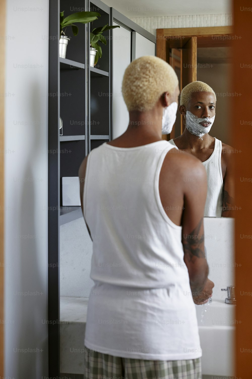 a man shaving his face in front of a mirror