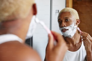 Ein Mann, der sich vor einem Spiegel das Gesicht rasiert