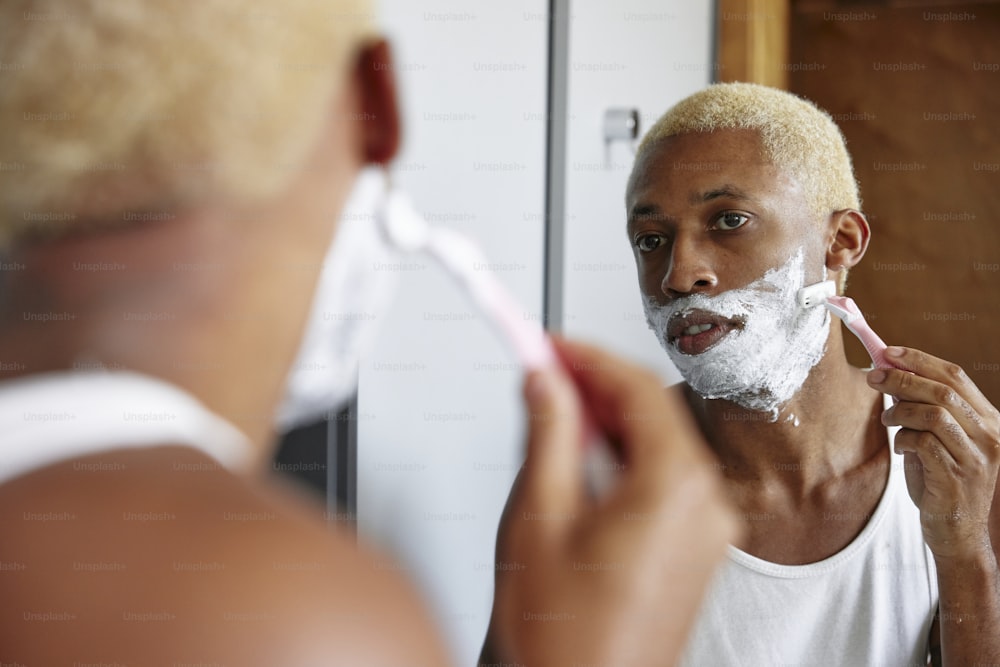 a man shaving his face in front of a mirror