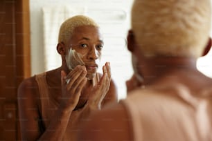 Un uomo che si rade la faccia davanti a uno specchio