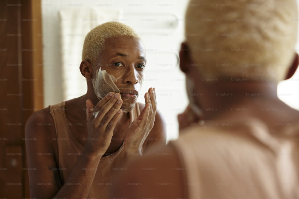 Un hombre afeitándose la cara frente a un espejo