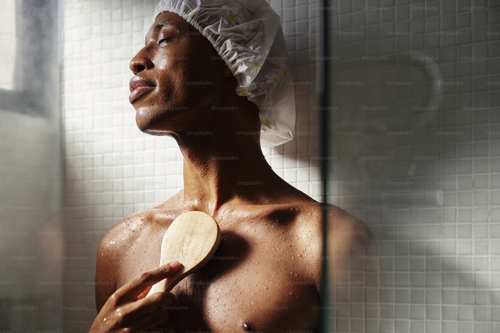 Un hombre sin camisa en una ducha sosteniendo una paleta de madera