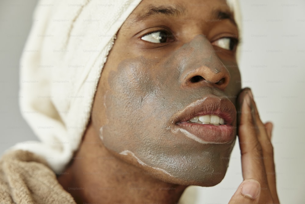 Un uomo con un asciugamano in testa si sta radendo la faccia
