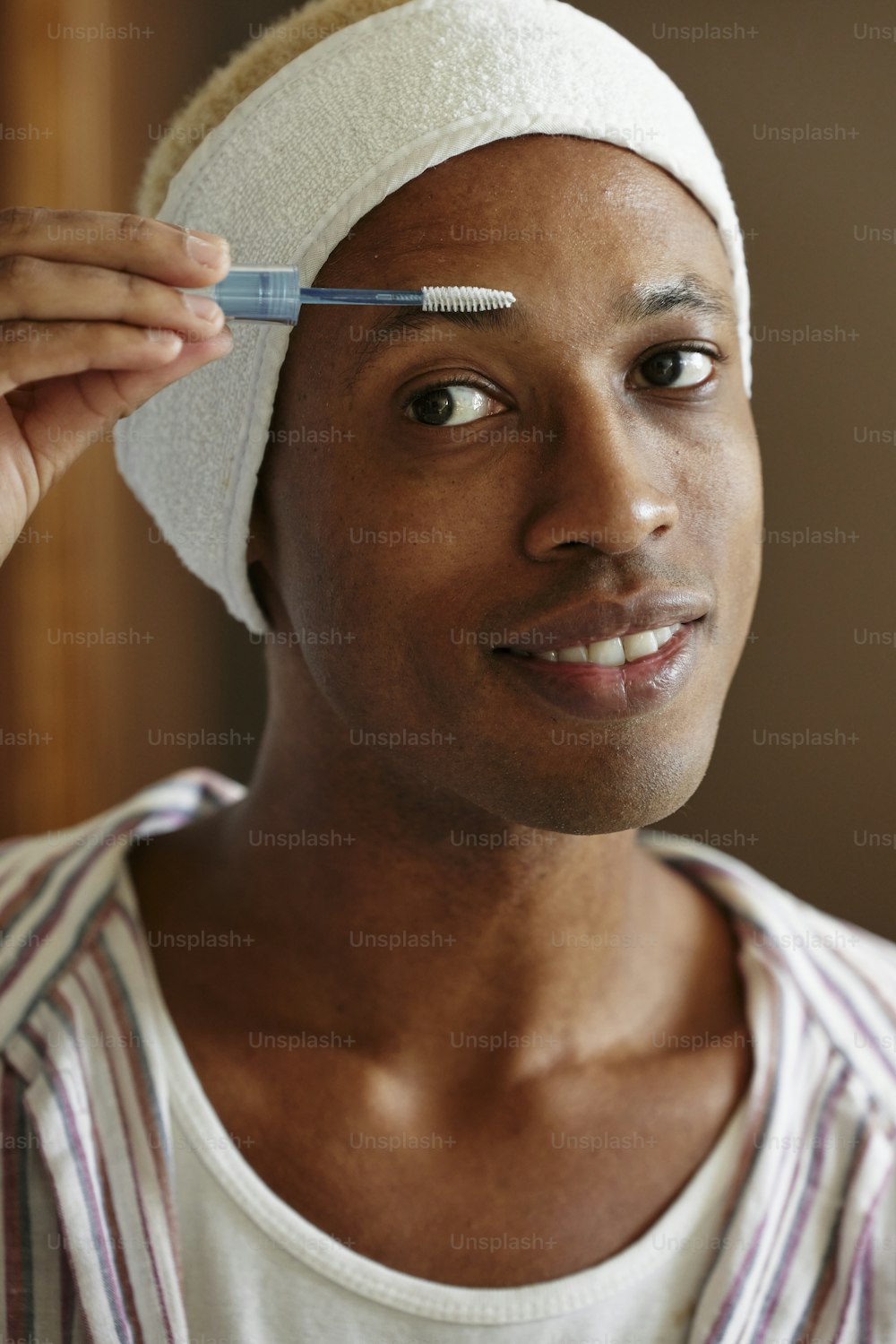 Un uomo con un asciugamano in testa che tiene uno spazzolino da denti