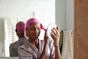 a man with pink hair is blow drying his hair