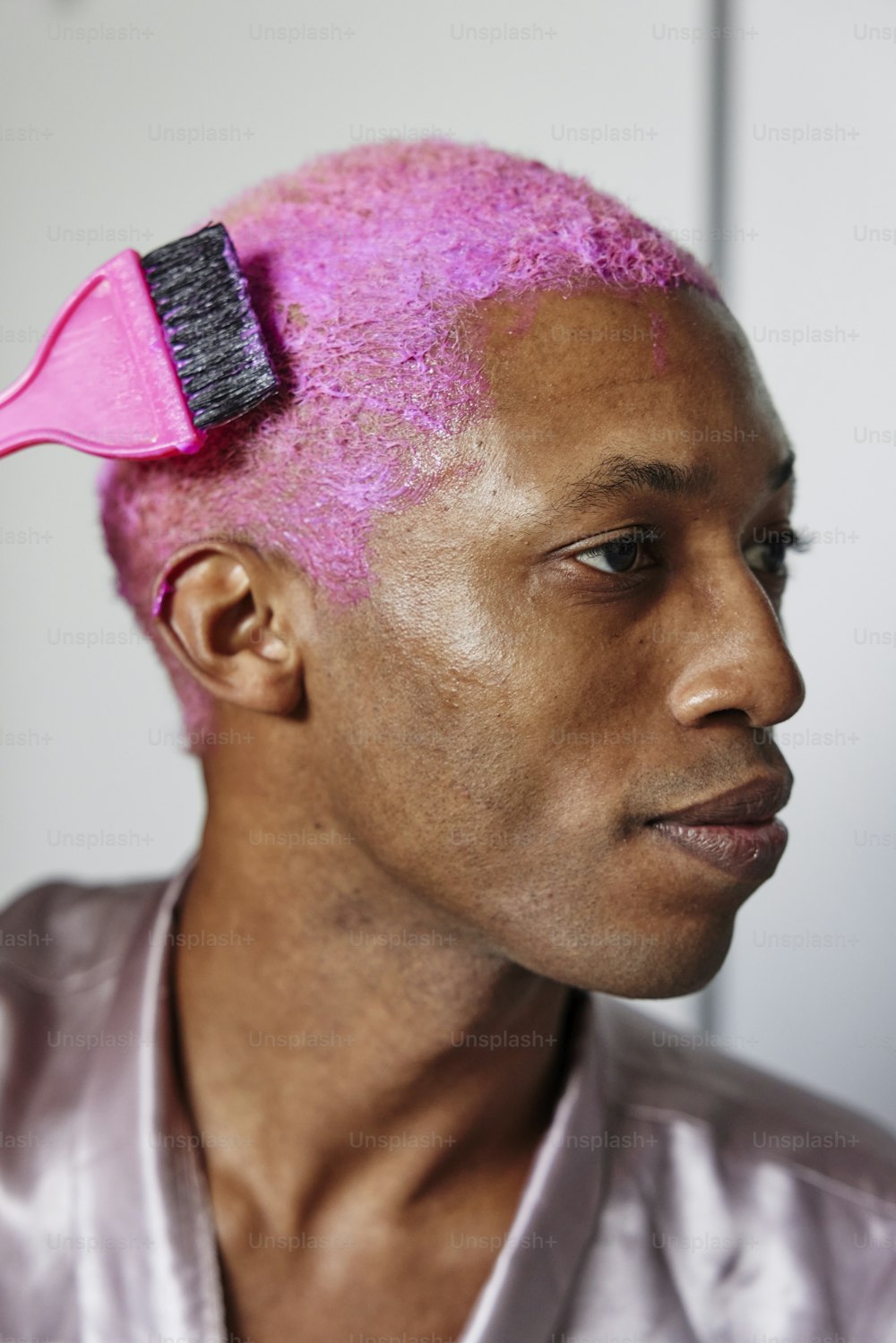 Un uomo con i capelli rosa e una spazzola tra i capelli