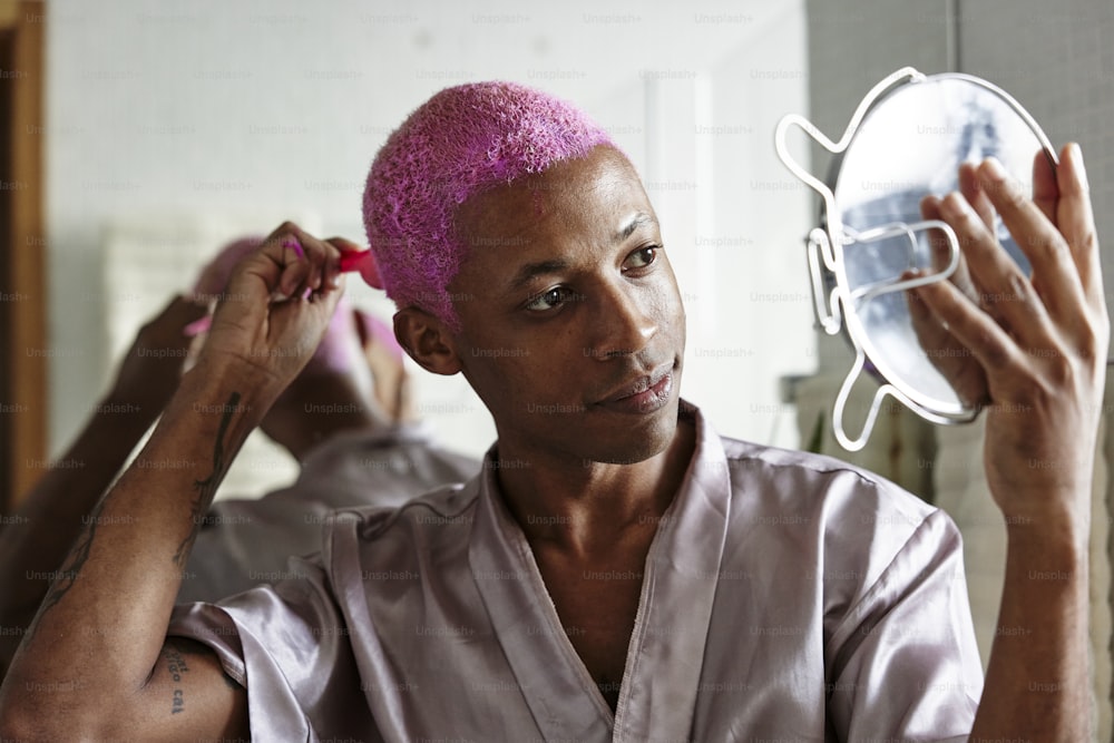 um homem com um moicano rosa está olhando em um espelho