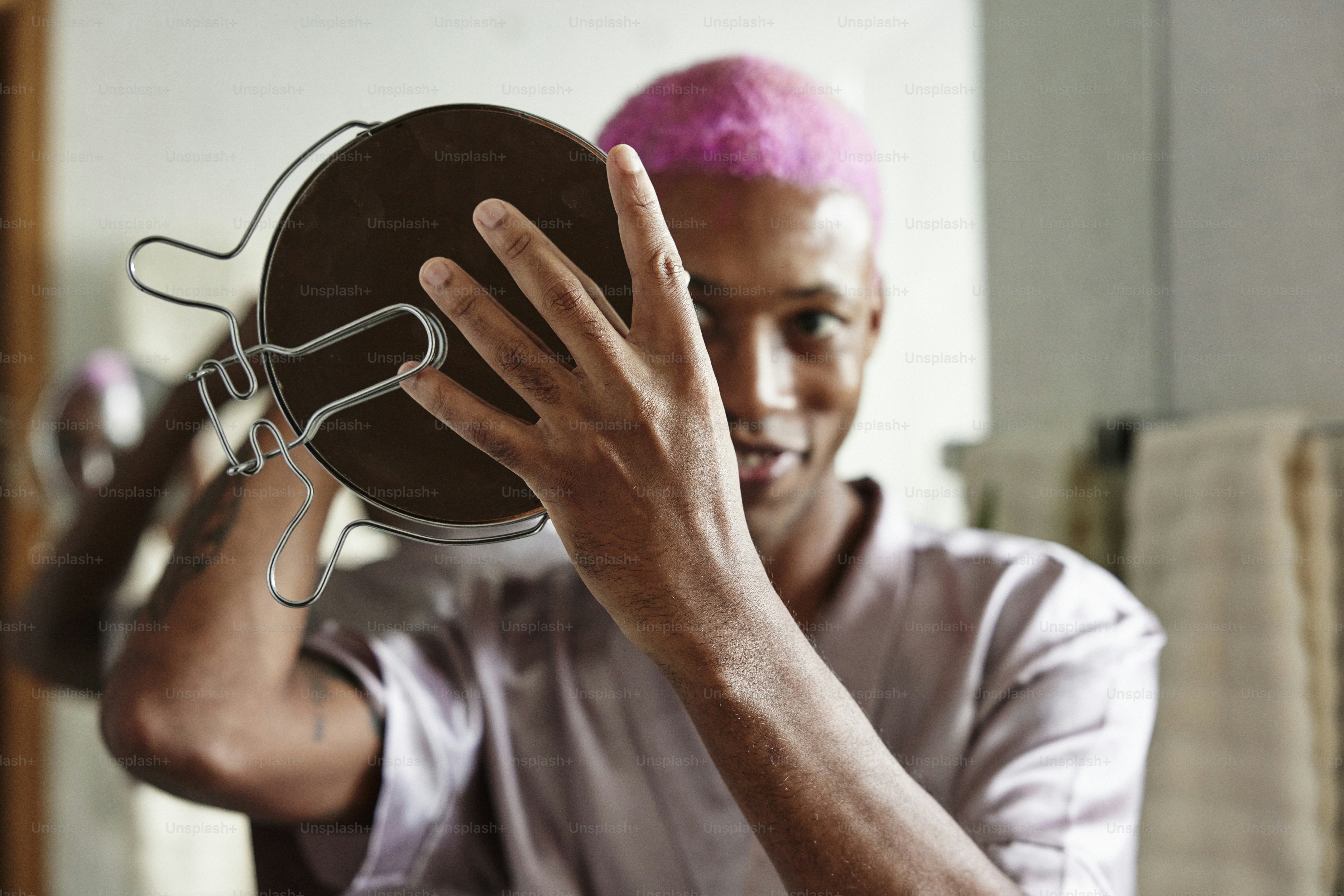 a man with pink hair holding up a metal object