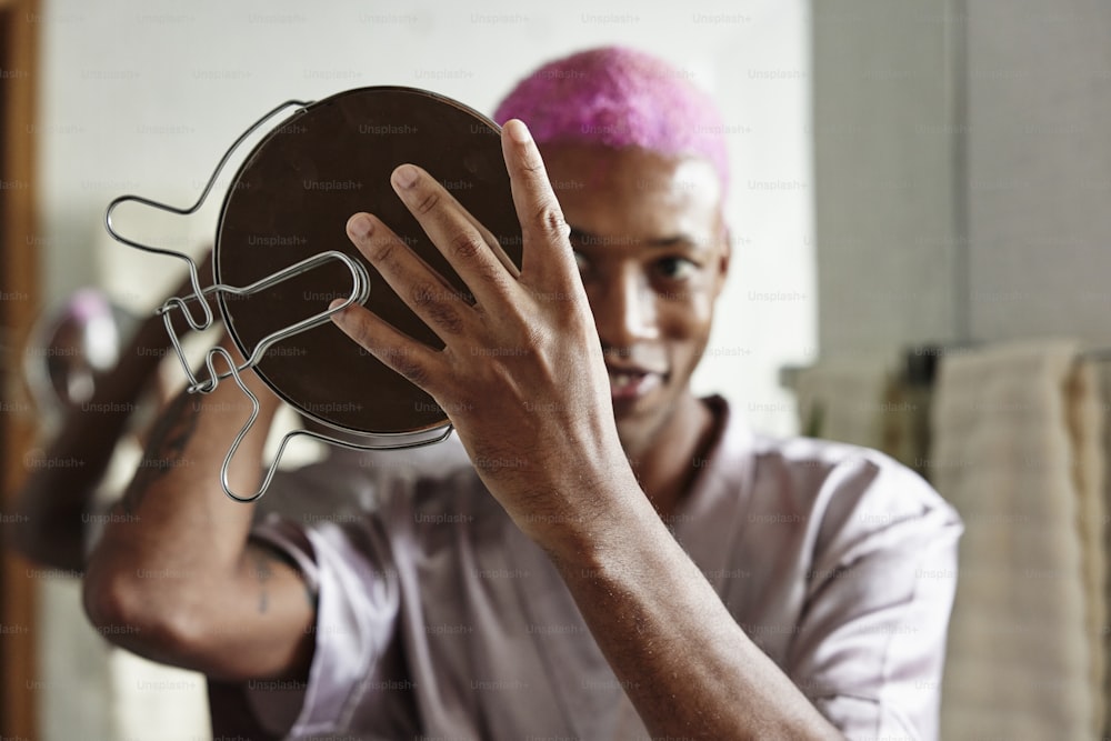 a man with pink hair holding up a metal object