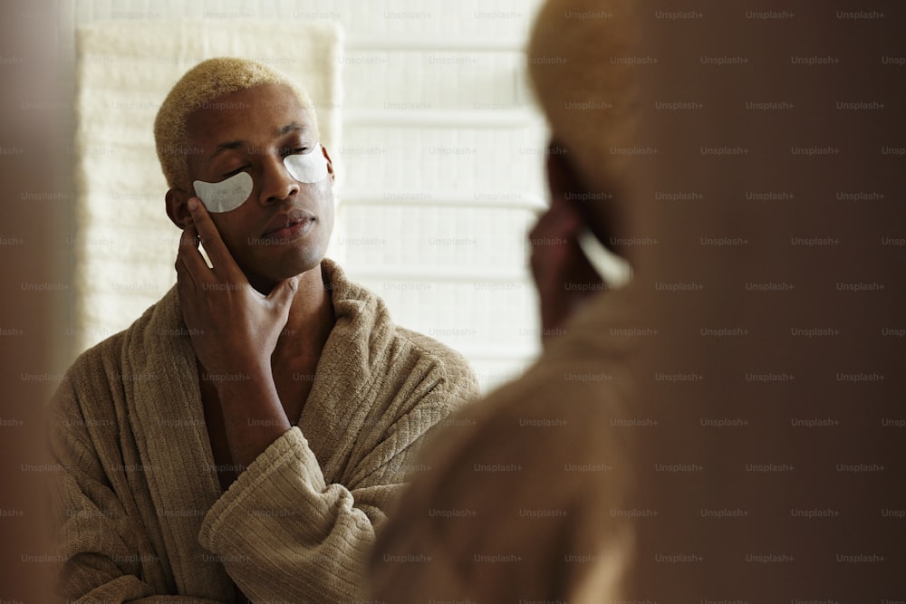 a man in a bathrobe looking at his reflection in a mirror