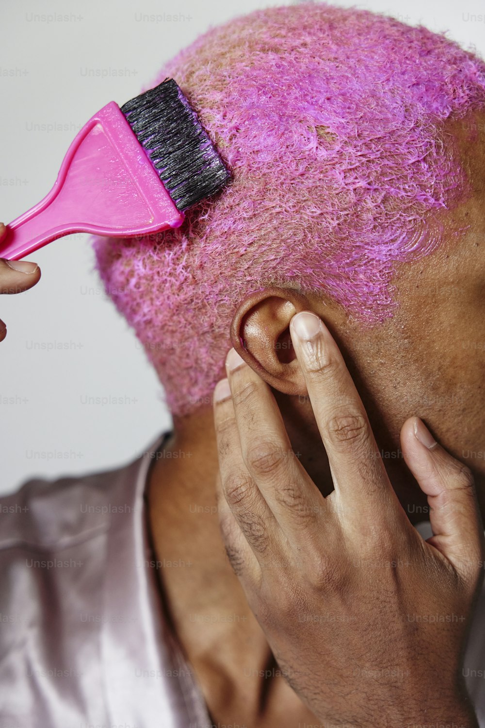 Un uomo con una spazzola per capelli rosa sulla testa