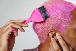 Une femme aux cheveux roses se brosse les cheveux
