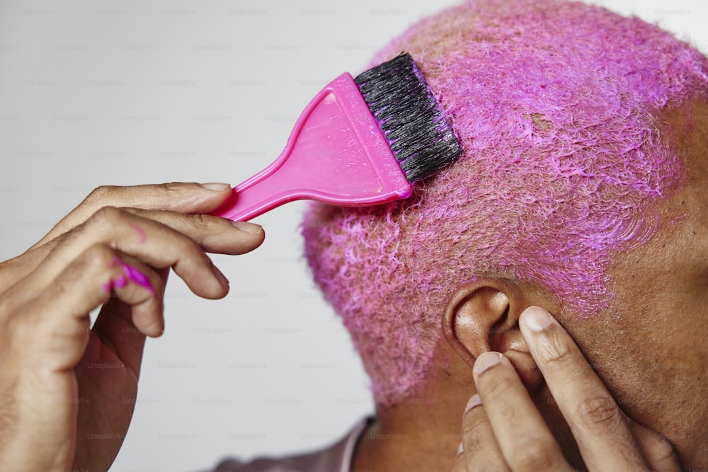 a woman with pink hair brushes her hair