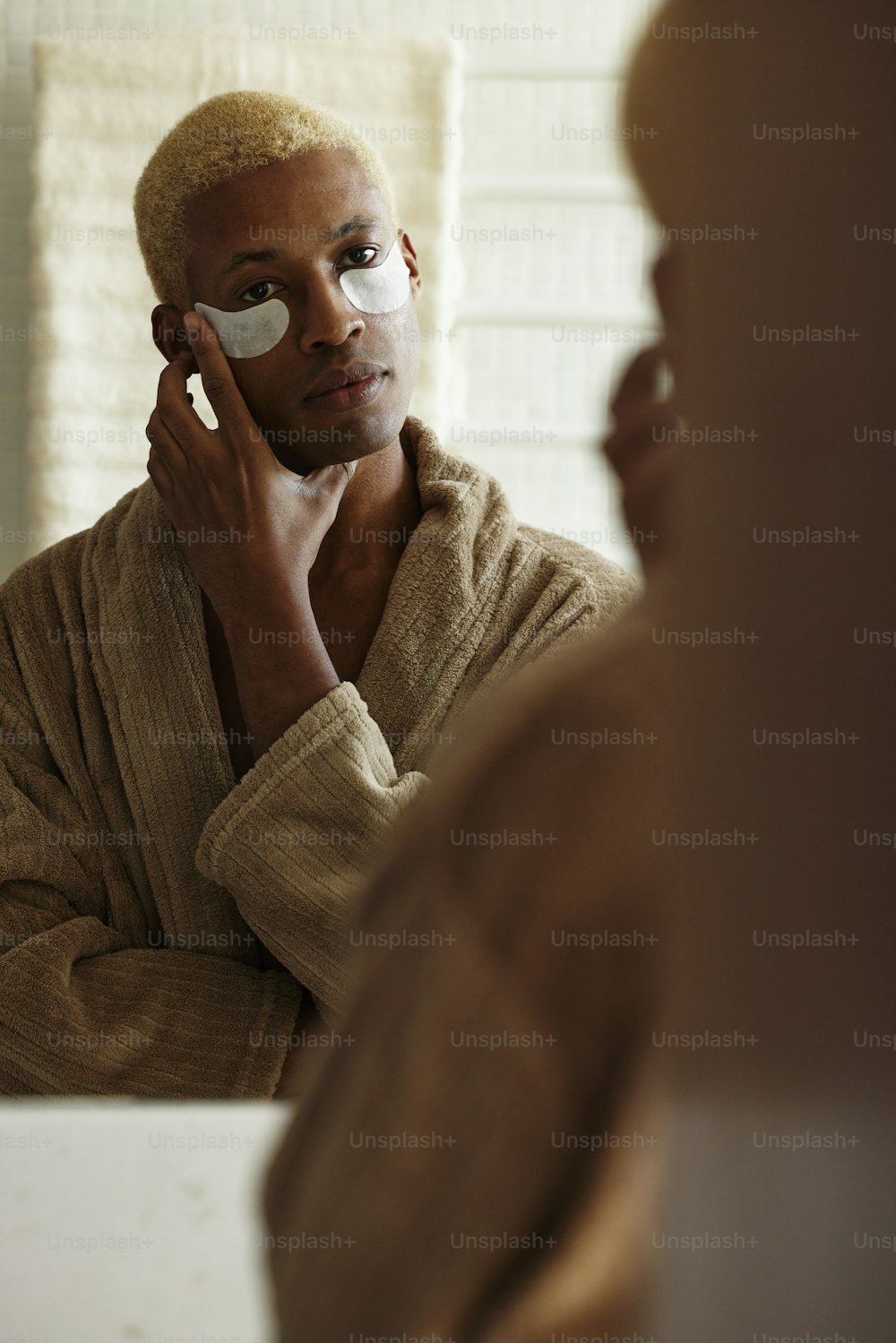 목욕 가운을 입은 남자가 얼굴을 면도하��고 있다