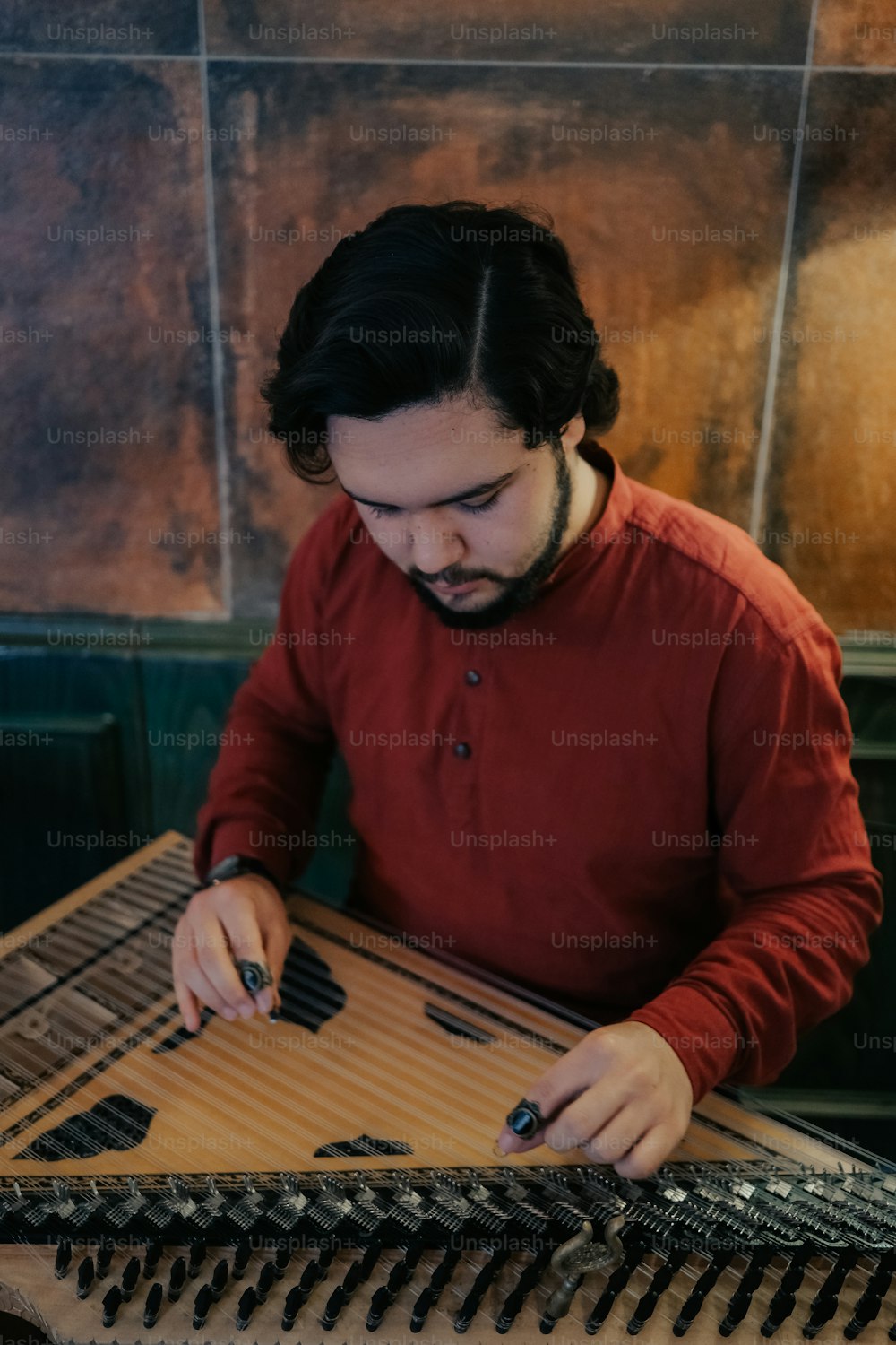a man sitting at a table working on a musical instrument