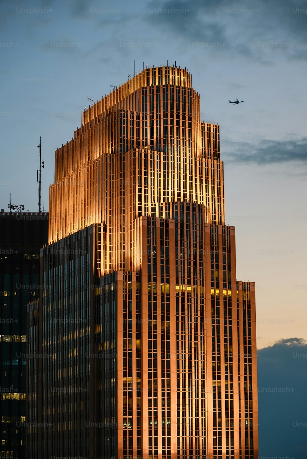 a very tall building with a plane flying in the sky