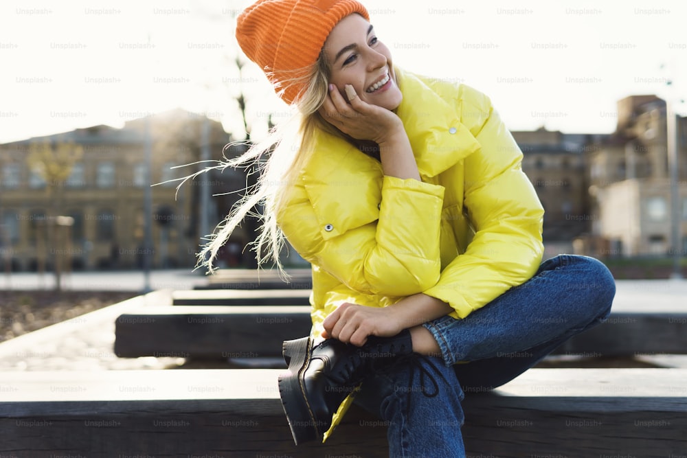 Porträt eines stilvollen Mädchens mit gelbem Puffer und orangefarbener Strickmütze