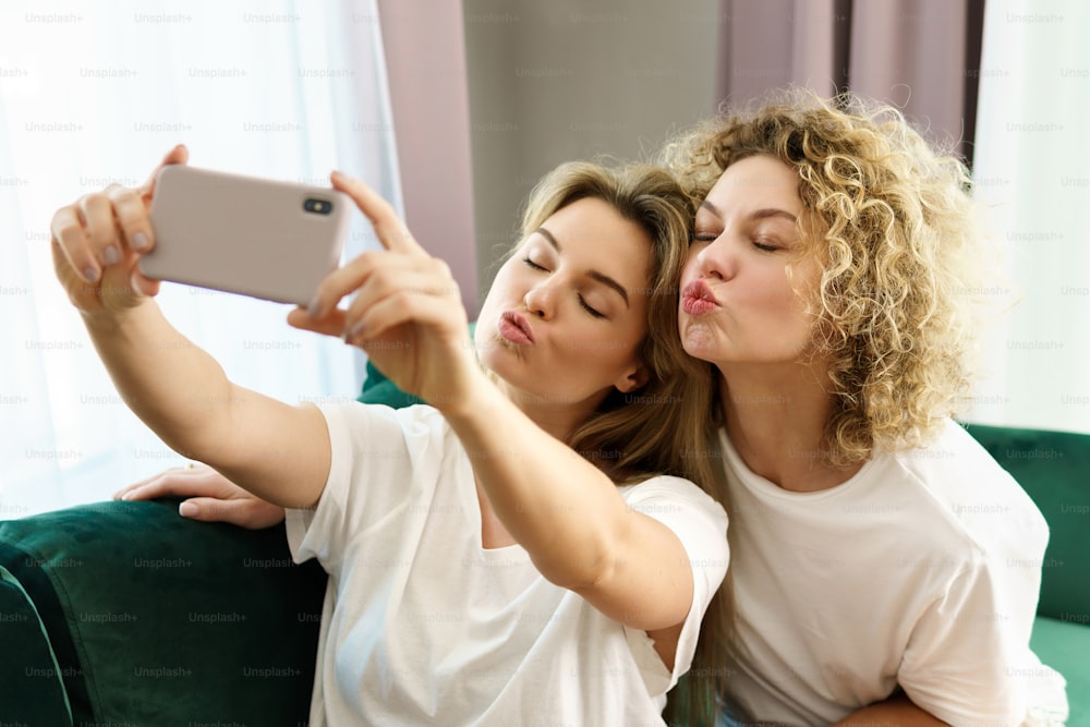 Deux jeunes filles joyeuses prenant un selfie ensemble à la maison