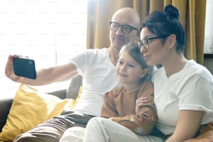 Happy and beautiful family taking selfie using smartphone at home