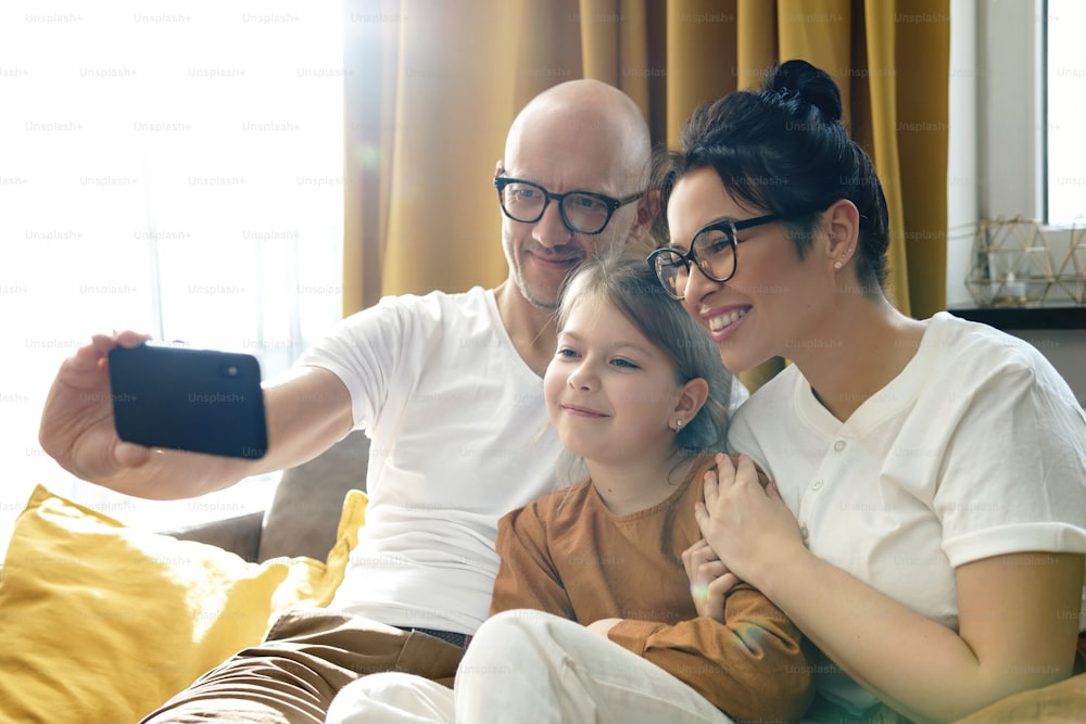 Happy and beautiful family taking selfie using smartphone at home