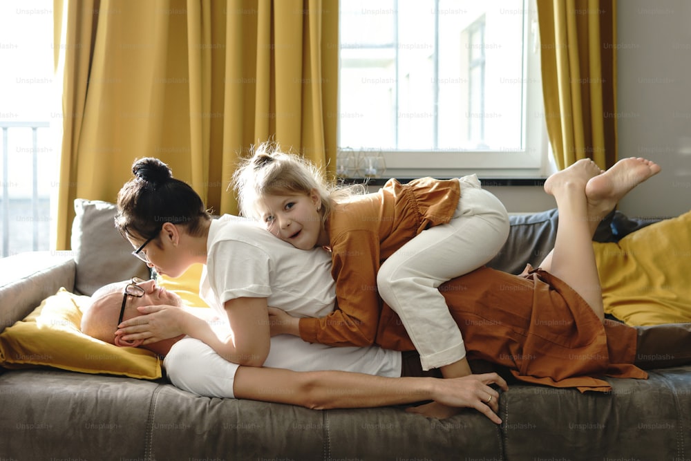 Familia joven y feliz acostada en el sofá y divirtiéndose en casa