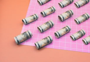 a bunch of rolled up money sitting on top of a pink surface