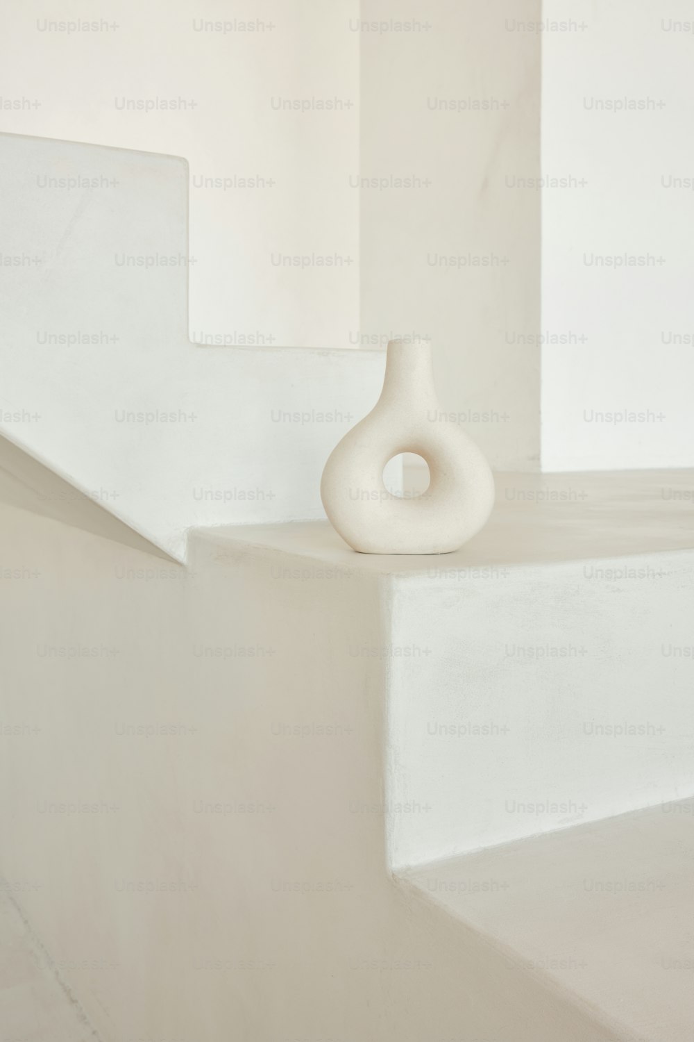un vaso bianco seduto sulla cima di una sporgenza bianca