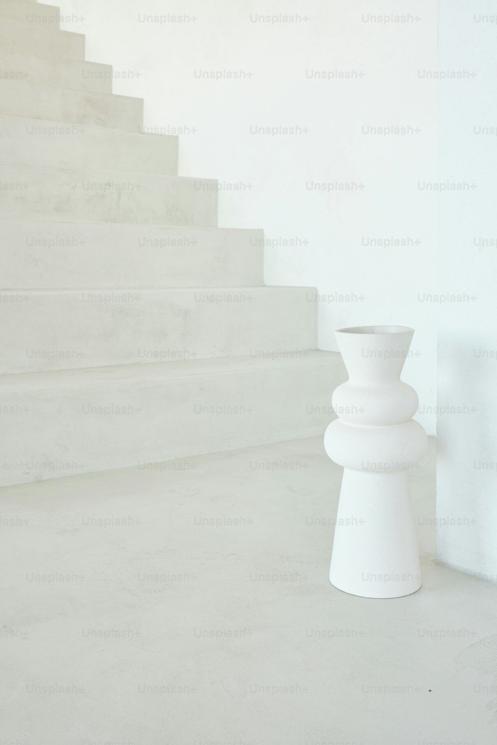 Un jarrón blanco sentado en la parte superior de un conjunto de escaleras