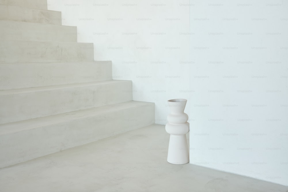 Un jarrón blanco sentado en la parte superior de un conjunto de escaleras