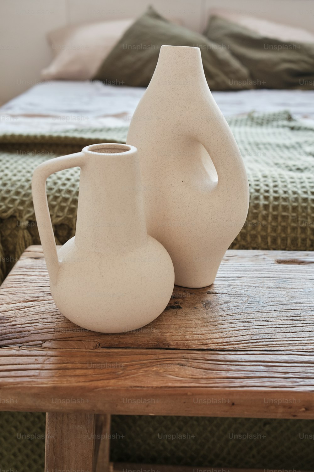 zwei weiße Vasen, die auf einem Holztisch sitzen