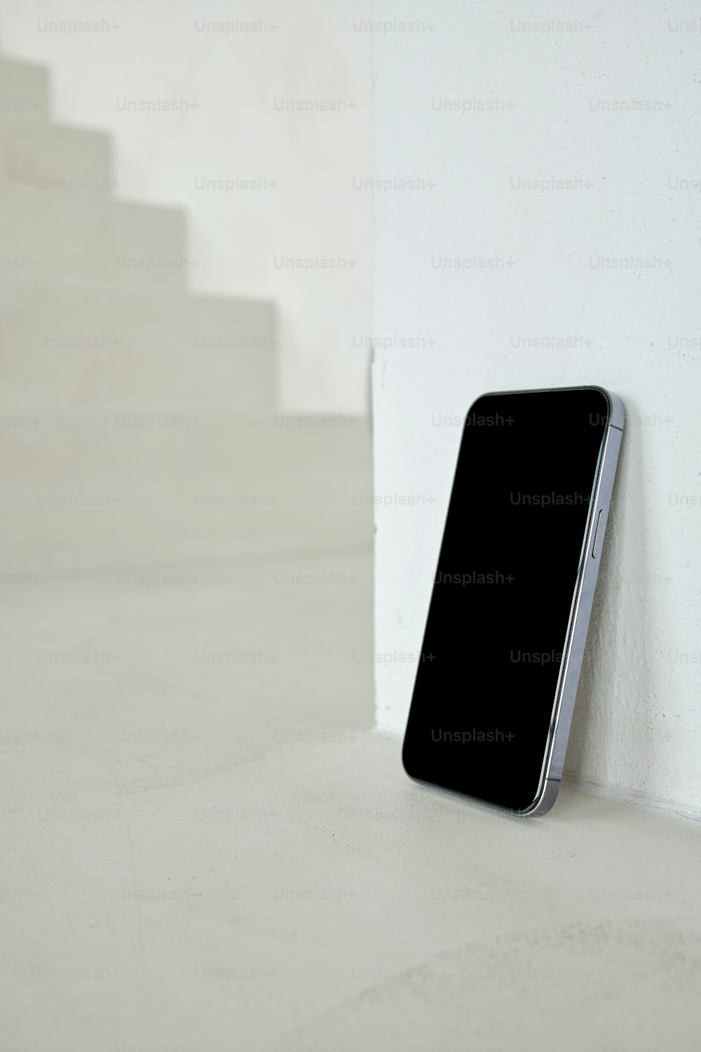 um telefone celular sentado no chão ao lado de um estojo de escada