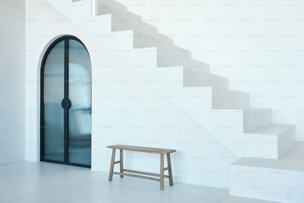 a wooden bench sitting in front of a white staircase