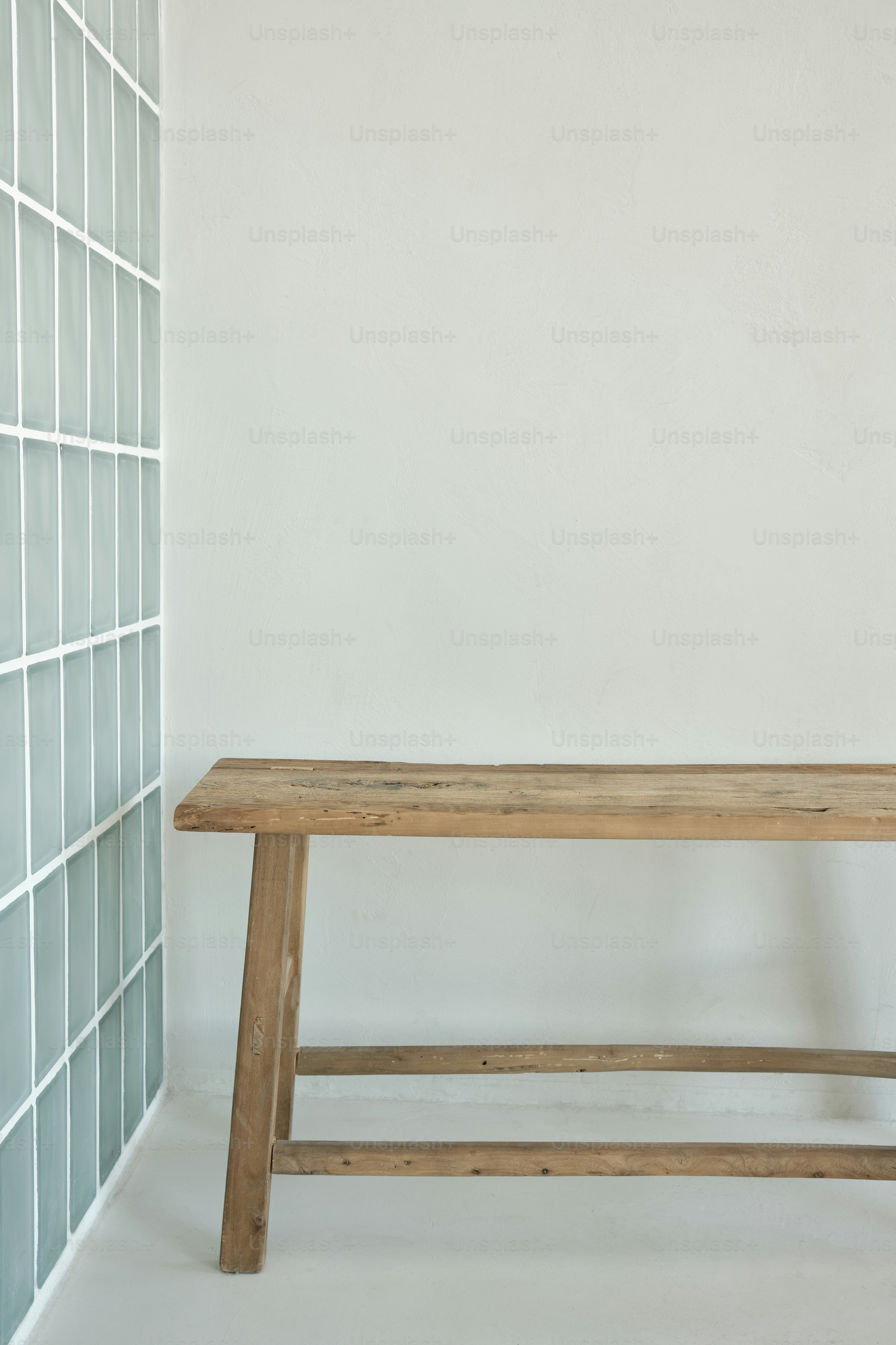 A wooden bench sitting in front of a white wall photo – Table mockup ...