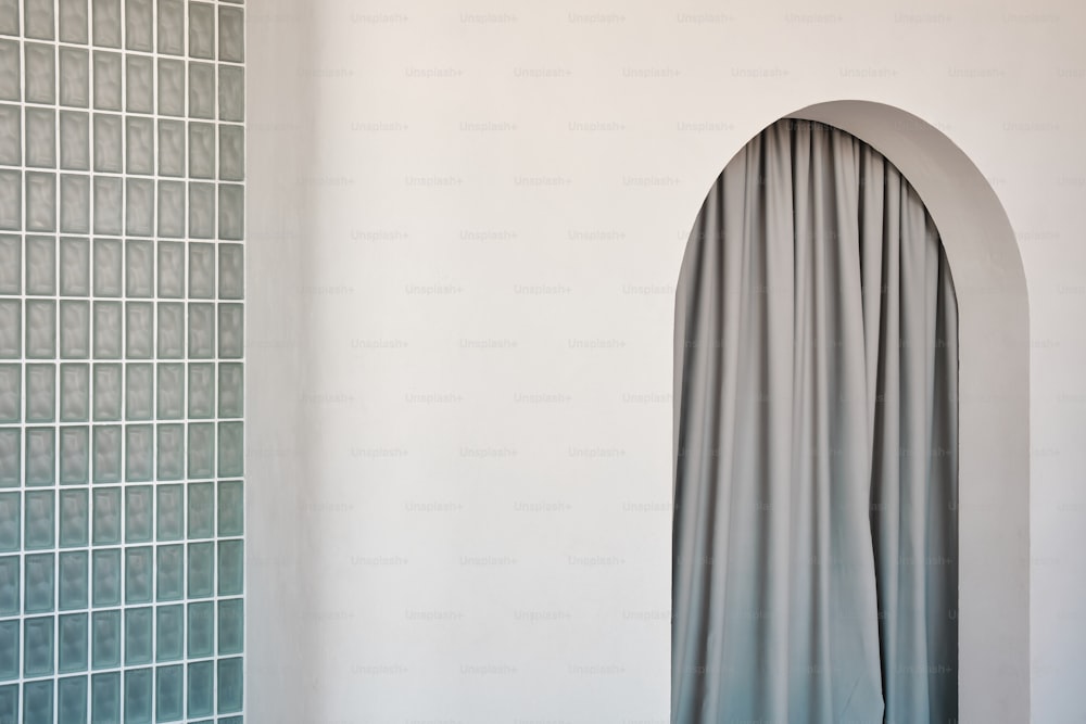 ein Raum mit einer weißen Wand und einem grauen Vorhang