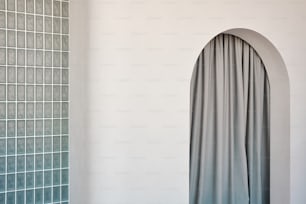 um quarto com uma parede branca e uma cortina cinza