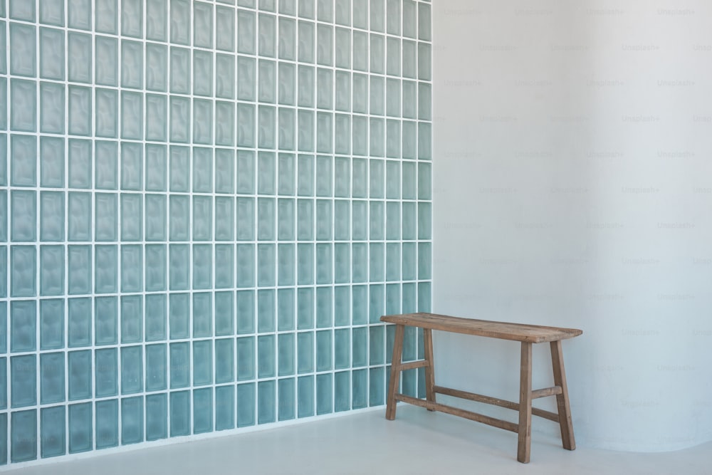 a wooden bench sitting in front of a blue tiled wall